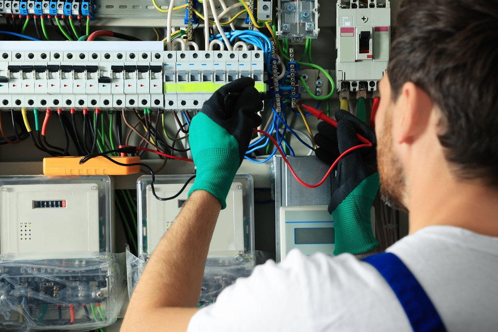 Electrician checking electric current with multimeter indoors, closeup
